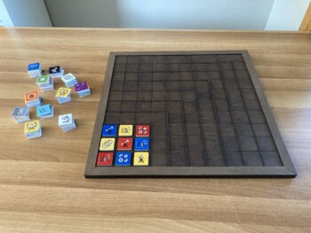 Houten bord met kleurrijke vierkante stukken. De verschillende kleuren en symbolen liggen sudokugewijs verdeeld.